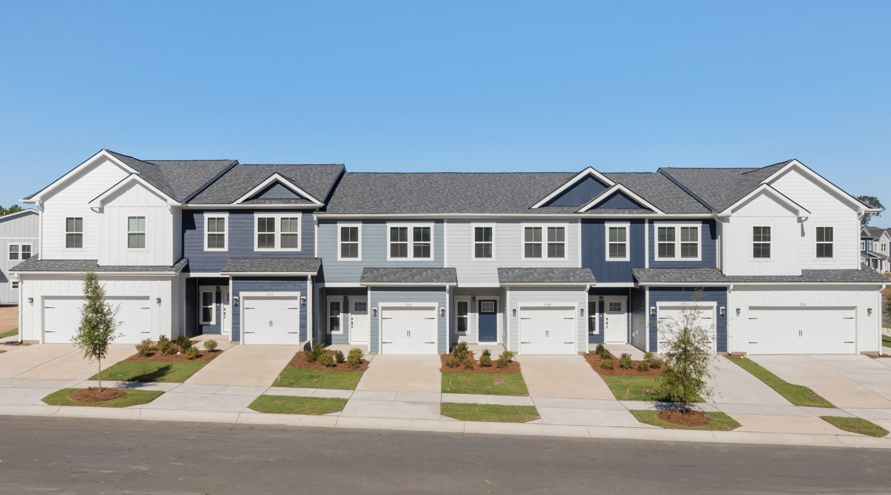 Two-story townhomes at Oaks at Wendell with attached garages, driveways, and landscaped front entrances.