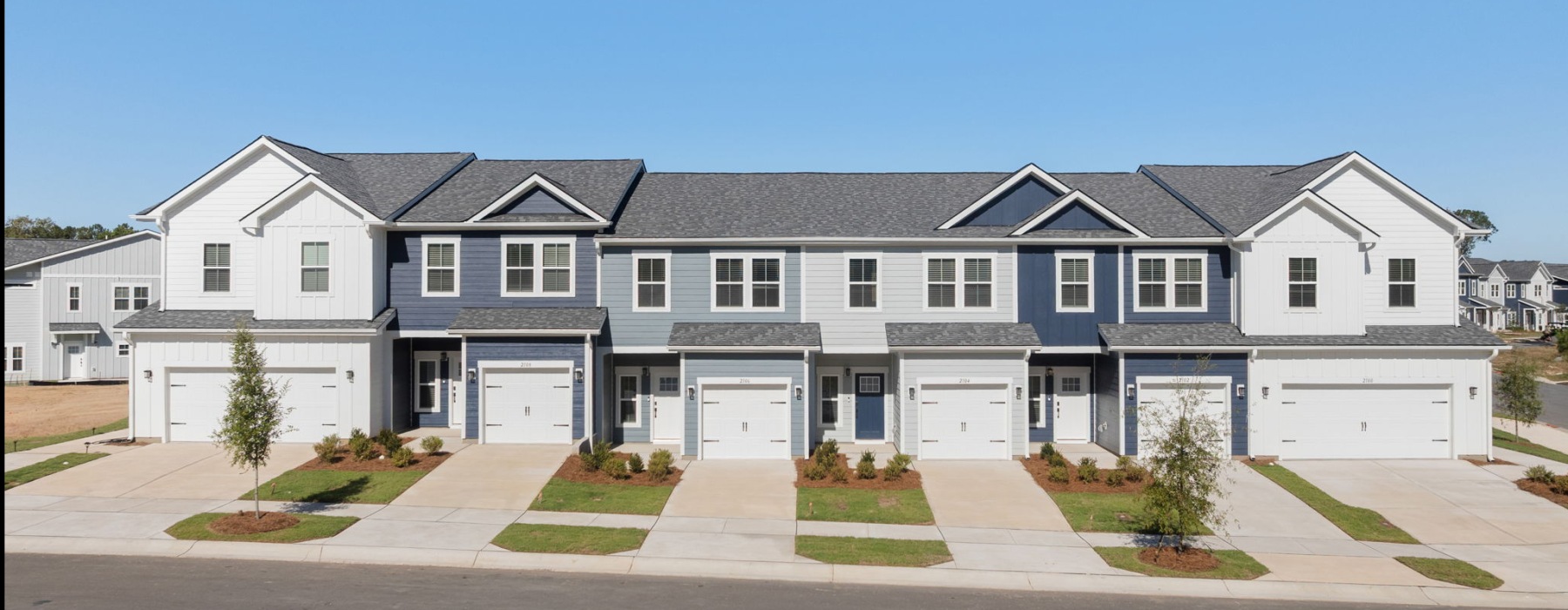 Two-story townhomes at Oaks at Wendell with attached garages, driveways, and landscaped front entrances.