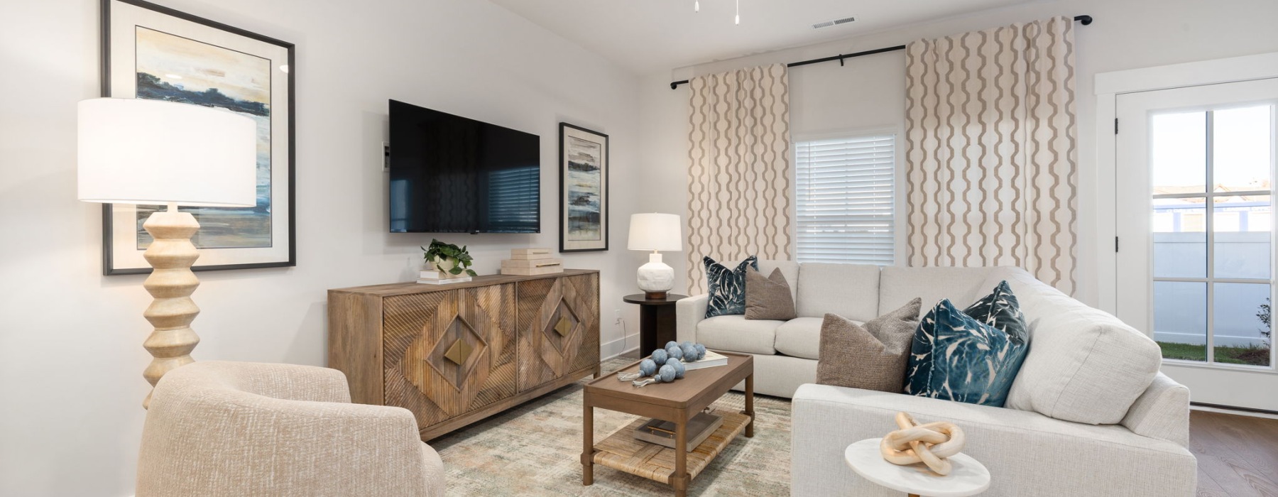 Living room at Oaks at Wendell with a sofa, accent chair, coffee table, and wall-mounted television.
